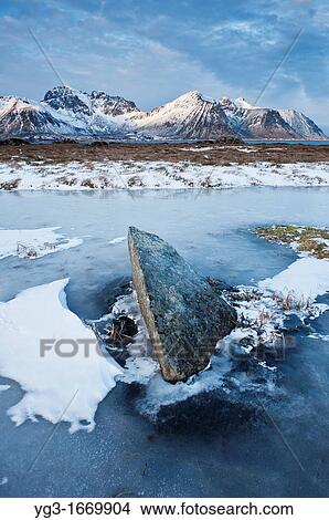 Rock emerges from frozen pond in winter, Lofoten Islands, Norway View Large Photo Image Picture - Rock emerges from frozen pond in winter, Lofoten Islands, Norway. Fotosearch