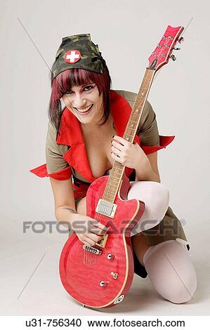 Stock Image - Rocker girl dressed as a nurse with a guitar. Fotosearch