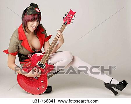 Stock Image - Rocker girl dressed as a nurse with a guitar. Fotosearch