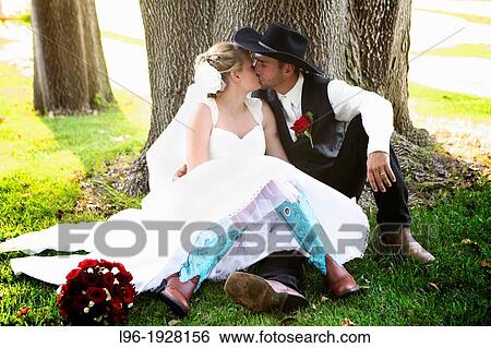 rodeo cowboy kissing his new wife wearing blue cowboy boots sitting together in a grove of trees in a private moment before the party View Large Photo Image Stock Photograph - rodeo cowboy kissing his new wife wearing blue cowboy boots sitting together in a grove of trees in a private moment before the party. Fotosearch