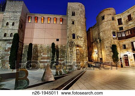Stock Image - Roman wall. Pla? a Nova Nova square. Palau del Bisbe Bishop Palace. Barcino statue, by Joan Brossa. Barcelona.. Fotosearch