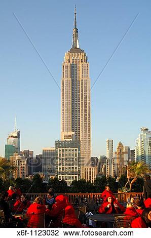 Stock Image - Roof-top terrace bar with view at the State Empire Building overtops all other high-rise buildings in Manhattan, New York, USA. Fotosearch