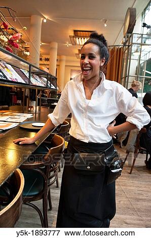 Stock Photo - Rotterdam, Netherlands. Young, colored waitress serving a customer in a grand-cafe restaurant, down town Rotterdam.. Fotosearch