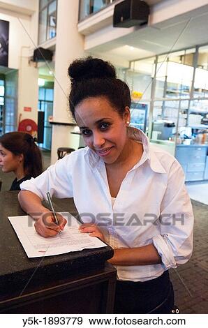 Stock Photo - Rotterdam, Netherlands. Young, colored waitress, signing a model release, after serving a customer in a grand-cafe restaurant, down town Rotterdam.. Fotosearch