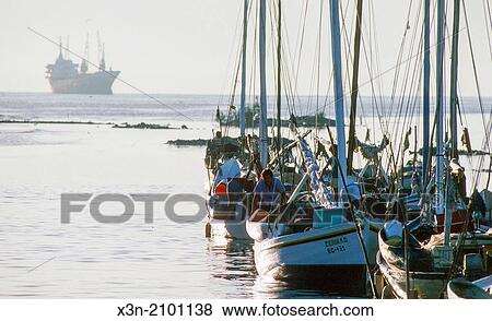 Row of boats moving towards large ship in ocean in Belize. View Large Photo Image Stock Photo - Row of boats moving towards large ship in ocean in Belize.. Fotosearch