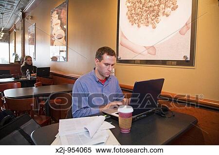 Royal Oak, Michigan - A man works on his laptop computer at Sweetwaters Cafe View Large Photo Image Stock Photography - Royal Oak, Michigan - A man works on his laptop computer at Sweetwaters Cafe. Fotosearch