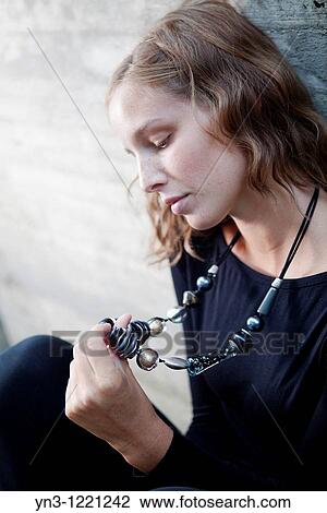 Sad girl looking down at her necklace View Large Photo Image Stock Image - Sad girl looking down at her necklace. Fotosearch