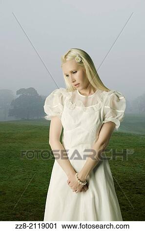 Stock Image - Sad woman standing in a misty field.. Fotosearch