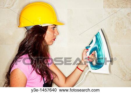 Stock Image - Safety Woman in kitchen Hard Hat/electric iron. Fotosearch