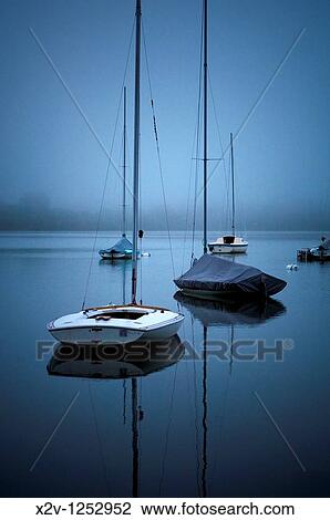 Stock Image - Sailboats on fog shrouded Lake Harriet at dawn. Fotosearch