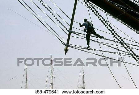 Stock Image - Sailor doing maintenance on tall ship. SAIL 2005. Amsterdam, Netherlands. Fotosearch