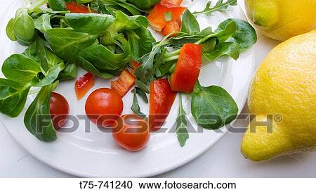Stock Image - Salad with lamb's lettuce, rocket, red pepper, cherry tomatoes and lemon. Fotosearch
