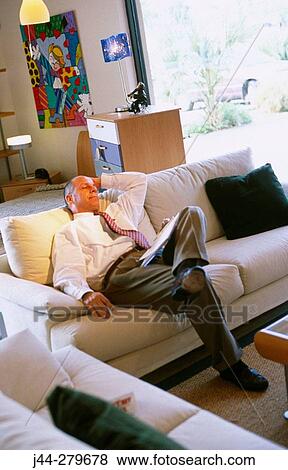 Stock Photo - Salesman resting on a sofa in a furniture store. Fotosearch