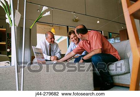 Salesman showing catalogs to a couple in a furniture store View Large Photo Image Stock Image - Salesman showing catalogs to a couple in a furniture store. Fotosearch