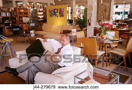 Salesman sitting on a sofa in a furniture store View Large Photo Image Stock Photo - Salesman sitting on a sofa in a furniture store. Fotosearch