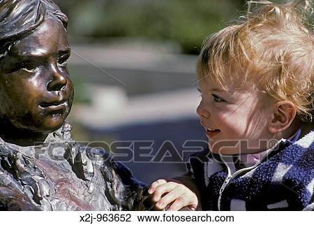 Santa Fe, New Mexico - Mariel West, not quite 2, studies the bronze likeness of a child playing on the grounds of the New Mexico state capitol MR View Large Photo Image Stock Image - Santa Fe, New Mexico - Mariel West, not quite 2, studies the bronze likeness of a child playing on the grounds of the New Mexico state capitol MR. Fotosearch