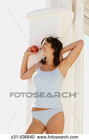 Stock Image - Santhi, Smiling, Apple, Underwear, Carefree, Knees-up. Fotosearch