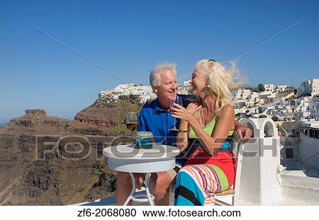 Santorini Greece retired couple on holiday having fun having wine on cliff in Fira Greek vacation. View Large Photo Image Stock Image - Santorini Greece retired couple on holiday having fun having wine on cliff in Fira Greek vacation.. Fotosearch