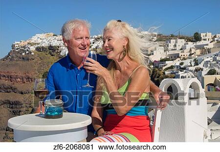 Santorini Greece retired couple on holiday having fun having wine on cliff in Fira Greek vacation. View Large Photo Image Stock Image - Santorini Greece retired couple on holiday having fun having wine on cliff in Fira Greek vacation.. Fotosearch