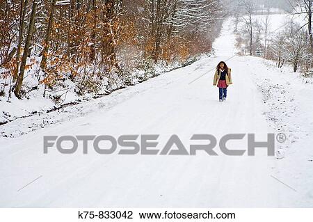 Stock Image - School girl walking on country road in the snow. Fotosearch
