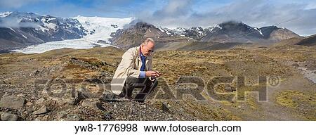 Stock Photo - Scientist investigating the landscape, Kviarjokull Glacier in background, Vatnajokull Ice Cap, Iceland. Fotosearch