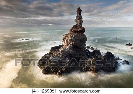 Stock Image - Sea stack off Tumbledown Bay, dawn, southern bays of Banks Peninsula, Canterbury, New Zealand.. Fotosearch