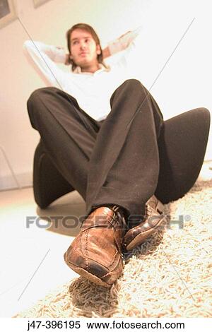 Selective focus on shoes, man sitting on chair with arms behind his head View Large Photo Image Stock Photography - Selective focus on shoes, man sitting on chair with arms behind his head. Fotosearch
