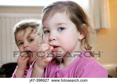Selective focus, two 3 year old girls eating fruit, looking into camera View Large Photo Image Stock Photo - Selective focus, two 3 year old girls eating fruit, looking into camera. Fotosearch