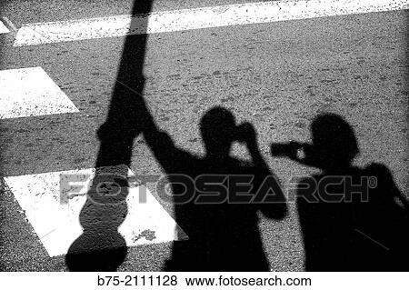 Self Portrait. Shadow of a couple leaning against a traffic light photographing themselves in Barcelona, Spain, Europe View Large Photo Image Stock Photo - Self Portrait. Shadow of a couple leaning against a traffic light photographing themselves in Barcelona, Spain, Europe. Fotosearch
