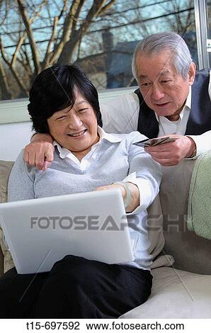 Stock Image - Senior asian couple enjoy time together shopping online. Fotosearch