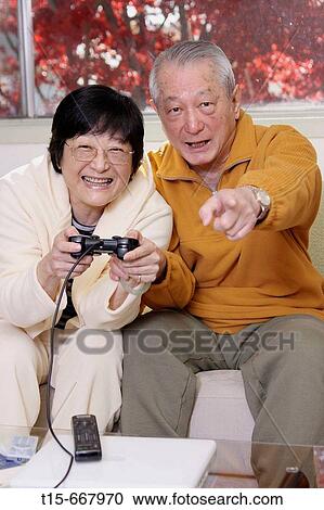 Senior Asian couple having fun playing video playstation games on tv View Large Photo Image Stock Image - Senior Asian couple having fun playing video playstation games on tv. Fotosearch