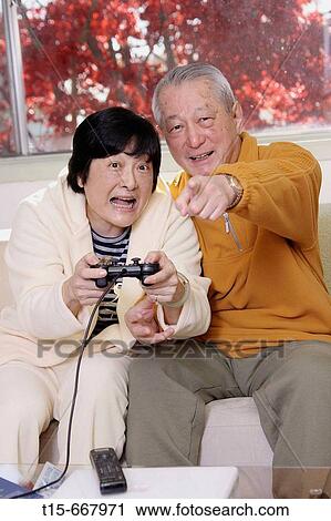 Senior Asian couple having fun playing video playstation games on tv View Large Photo Image Stock Image - Senior Asian couple having fun playing video playstation games on tv. Fotosearch