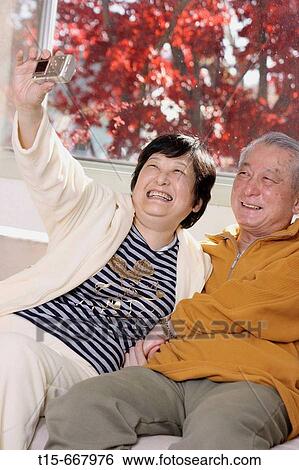 Senior Asian couple sitting on safa taking a self portrait View Large Photo Image Stock Photograph - Senior Asian couple sitting on safa taking a self portrait. Fotosearch