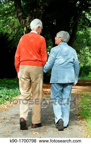 Senior caucasian couple, holding their hands while walking and seen from backside, blurred background, Hamburg, Germany, Europe View Large Photo Image Stock Photo - Senior caucasian couple, holding their hands while walking and seen from backside, blurred background, Hamburg, Germany, Europe. Fotosearch