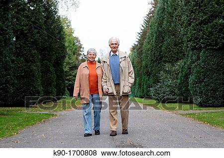 Senior caucasian couple, looking happy at the camera while walking through a park, blurred green background, Hamburg, Germany, Europe View Large Photo Image Stock Photo - Senior caucasian couple, looking happy at the camera while walking through a park, blurred green background, Hamburg, Germany, Europe. Fotosearch