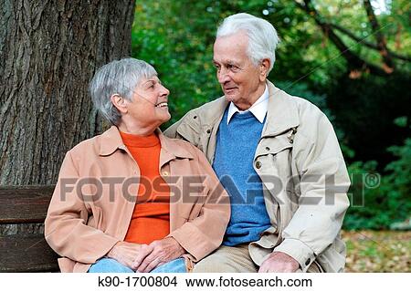 Senior caucasian couple sitting on a bench in a park with nature in the background, looking at each other, Hamburg, Germany, Europe View Large Photo Image Picture - Senior caucasian couple sitting on a bench in a park with nature in the background, looking at each other, Hamburg, Germany, Europe. Fotosearch