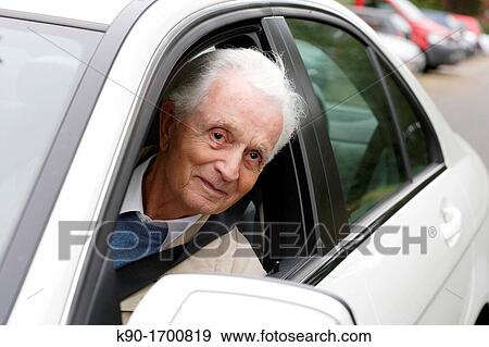 Stock Photo - Senior caucasian driving a white car and looking out of the window, Hamburg, Germany, Europe. Fotosearch