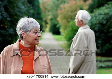 Senior caucasian woman with glasses, looking to the side with senior man seen from backside, blurred green background, Hamburg, Germany, Europe View Large Photo Image Picture - Senior caucasian woman with glasses, looking to the side with senior man seen from backside, blurred green background, Hamburg, Germany, Europe. Fotosearch