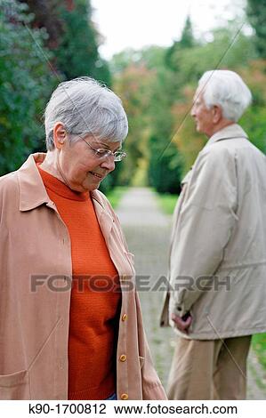 Senior caucasian woman with glasses, looking down with senior man in the background seen from behind, blurred green background, Hamburg, Germany, Europe View Large Photo Image Stock Image - Senior caucasian woman with glasses, looking down with senior man in the background seen from behind, blurred green background, Hamburg, Germany, Europe. Fotosearch