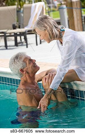 Stock Photography - Senior couple enjoying swimming pool. Fotosearch