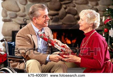 Stock Image - Senior couple exchanging Christmas presents. Fotosearch