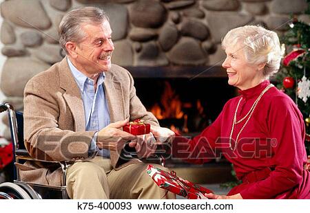 Stock Image - Senior couple exchanging presents at Christmas. Fotosearch