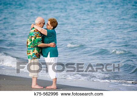 Stock Photograph - Senior couple hugging at the beach. Fotosearch