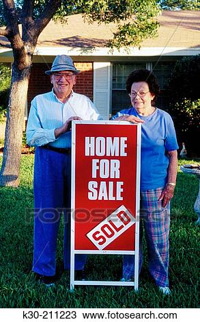 Senior couple in front of home for sale with sign View Large Photo Image Stock Image - Senior couple in front of home for sale with sign. Fotosearch