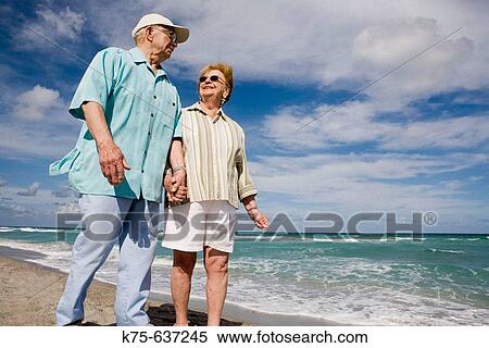 Stock Photography - Senior couple strolling along beach. Fotosearch