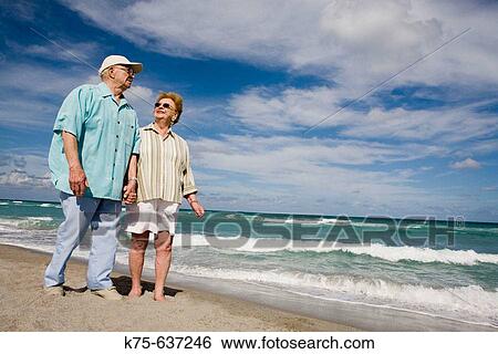 Senior couple strolling hand in hand along beach View Large Photo Image Stock Photograph - Senior couple strolling hand in hand along beach. Fotosearch