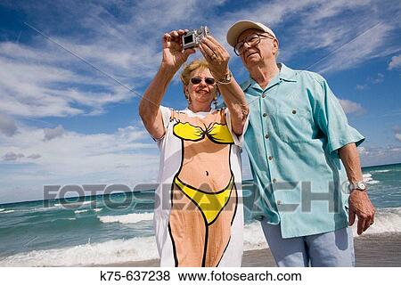 Stock Photo - Senior couple taking fun photo at beach.. Fotosearch