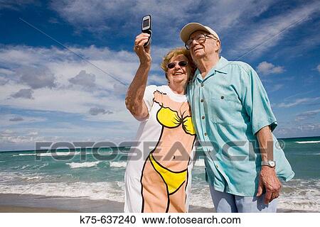 Stock Image - Senior couple taking picture with camera phone. Fotosearch