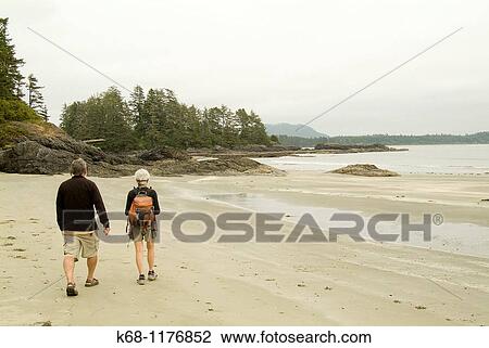 Stock Image - senior couple walk on beach near Tofino, West Coast, Vancouver Island, British Columbia, Canada. Fotosearch
