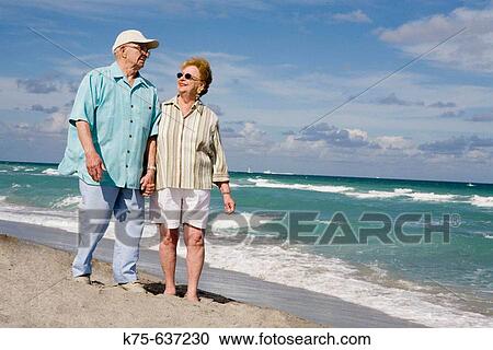 Senior couple walking hand in hand on beach View Large Photo Image Stock Image - Senior couple walking hand in hand on beach. Fotosearch